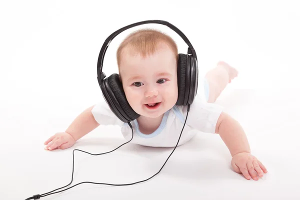 Encantador bebé sobre un fondo blanco con auriculares escuchando — Foto de Stock