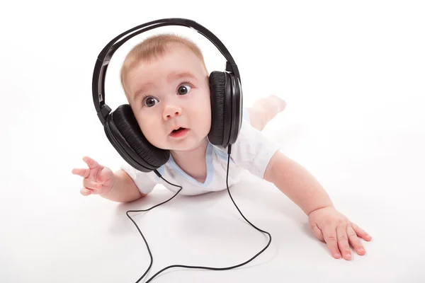 Encantador bebé sobre un fondo blanco con auriculares escuchando — Foto de Stock