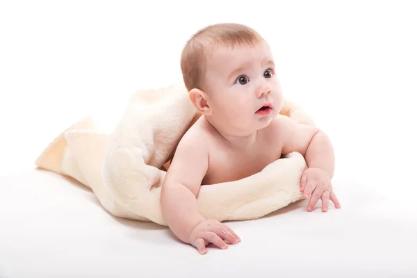 Alasti hymyilevä vauva makaa vatsallaan valkoisella taustalla — kuvapankkivalokuva