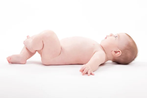 Alaston vauva makaa selällään ja katsoo kameraan — kuvapankkivalokuva