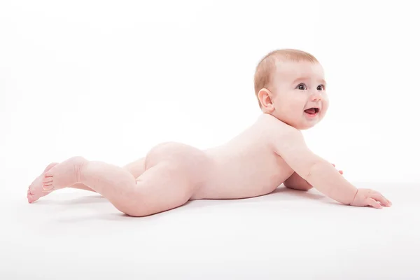 Desnudo sonriente bebé acostado sobre su estómago sobre un fondo blanco un —  Fotos de Stock