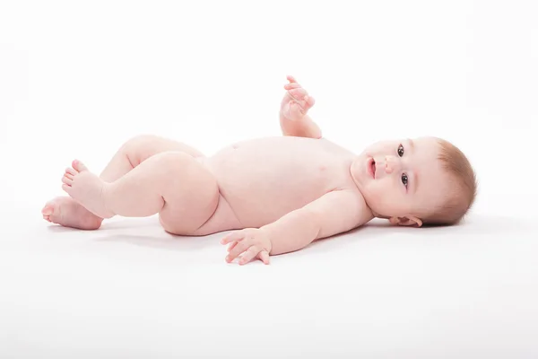 Naked baby lies on his back and looks at the camera Stock Image