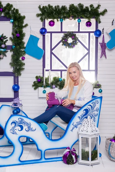 Sexig blondin sitter på en Christmas släde på en vit terrass sur — Stockfoto