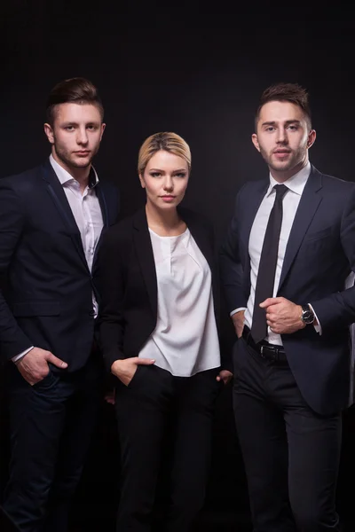 Team of three successful stylish young lawyers on a black backgr