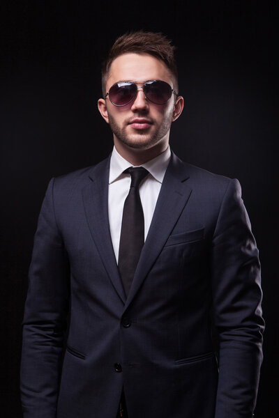 stylish, trendy businessman in a business suit and sunglasses on
