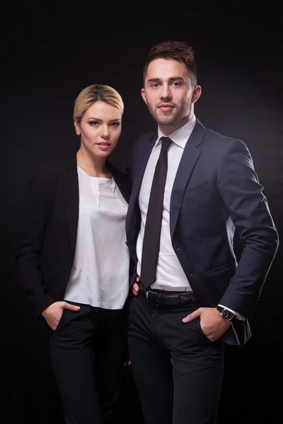 Hombre y mujer de negocios elegantes, modernos y de moda en el respaldo negro — Foto de Stock