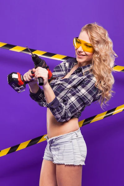 Сексуальный блондин-строитель с отвёрткой на фиолетовом пакете — стоковое фото