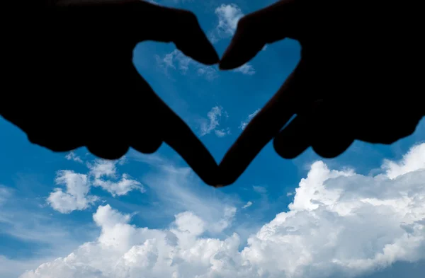 Liefde vorm hand silhouet in de blauwe lucht en cloud — Stockfoto