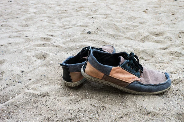 Alte Turnschuhe im Sand am Strand. Vorgeschichte. — Stockfoto