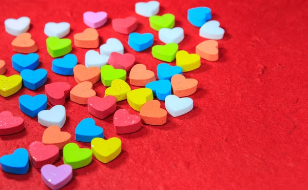 Alla hjärtans dag bakgrund med färgglada hjärtformade på röda pape — Stockfoto
