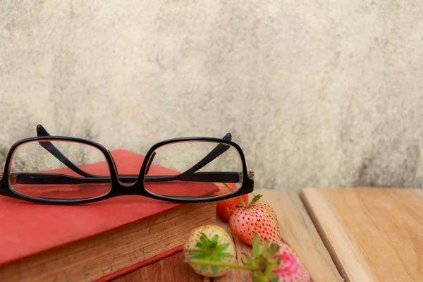 Glasses, Book, Strawberry on wooden and background of old wall. — Stock Photo, Image