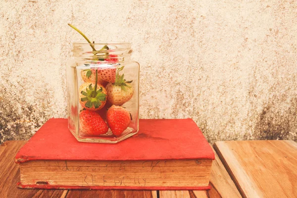 Pot de fraises et un livre sur le bois, couleur de processus avec Vintage — Photo