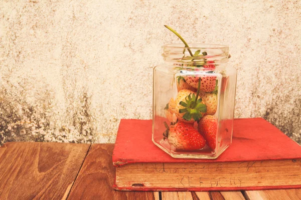 Pot de fraises et un livre sur le bois, couleur de processus avec Vintage — Photo