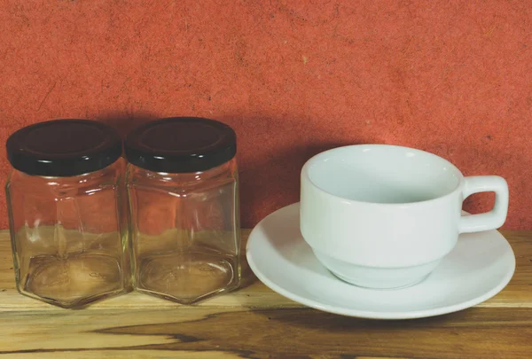 Copo de café vazio e frasco vazio em uma cor de madeira, processo com V — Fotografia de Stock