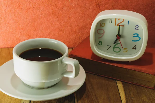 'S ochtends koffie klok en een boek, over een houten tafel. Proces colo — Stockfoto