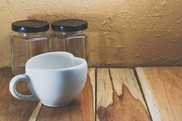 Weiße Kaffeetasse und leeres Glas auf einem hölzernen. Prozessfarbe mit v — Stockfoto