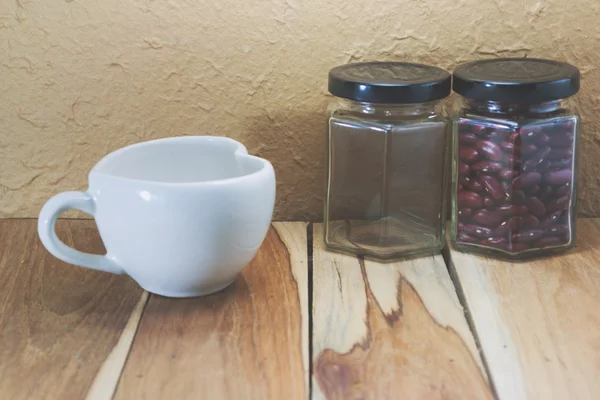 Weiße Kaffeetasse und leeres Glas auf einem hölzernen. Prozessfarbe mit v — Stockfoto