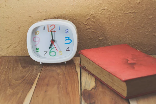 Clock and a book on wooden. Process color with vintage tone. — Stock Photo, Image