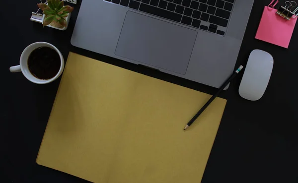 Business desk with laptop and memo paper placed on a black background, including a copy area to add text or graphics.