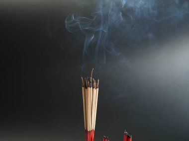 Tütsü yakan siyah dumanlı arka plan tapınma arkaplanı olarak kullanılan Budist inançlarının kutsal bir nesnesi dumana odaklanır..