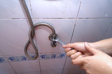 Tamircinin biri evin tuvaletinde bozuk bir musluk borusunu sökmek için pense kullanıyor..