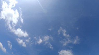 Düşük açılı zaman çizelgesi. Mavi gökyüzünde, öğlen güneşinin tam zamanı. Güneş, yaz ufkunda, parlak güneş ışığı altında, güneş ışığı, öğlen güneşinde beyaz kümülüs bulutlarıyla parlıyor..