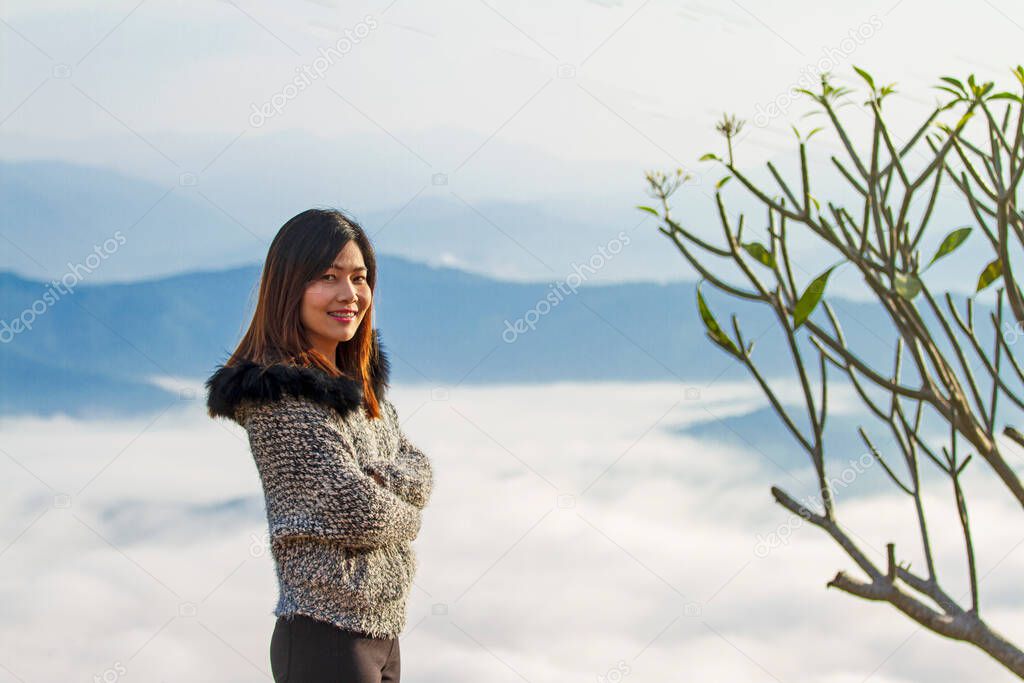 Portrait of the charming young woman stand happily watching the morning mist.