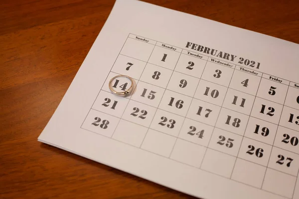 Calendar on which the date is 14 February. Valentines Day. Wedding ring on the calendar.