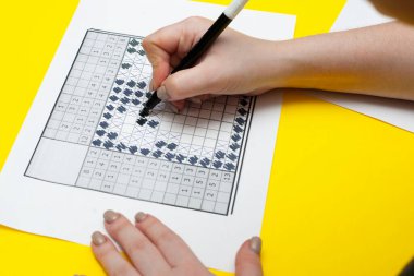 Bir kadın Japon bulmacasını çözüyor. Sarı arka planda Japon bulmacası. Yüksek kalite fotoğraf