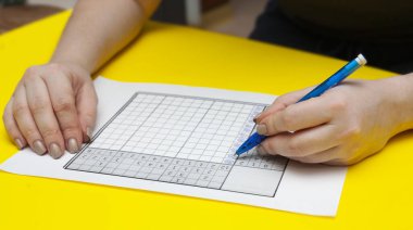 Kadın sol eliyle Japon çapraz bulmacasını çözüyor. Solak. Yüksek kalite fotoğraf