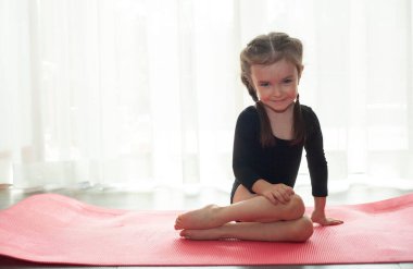Küçük kız jimnastik yapıyor. Evde yoga yapan bir kız.