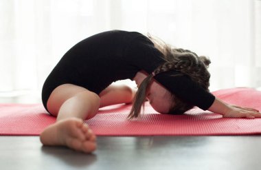 Küçük kız jimnastik yapıyor. Evde yoga yapan bir kız.