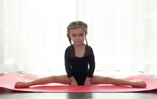 Little girl doing gymnastic exercise. Girl doing yoga at home