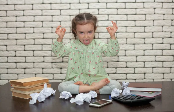 Little girl at the desktop meditates. The working process. Business con