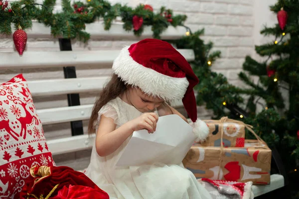 Una Bambina Con Cappello Babbo Natale Guarda Una Busta Lettera — Foto Stock