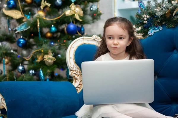 Little girl talking on a laptop. Happy New Year online.