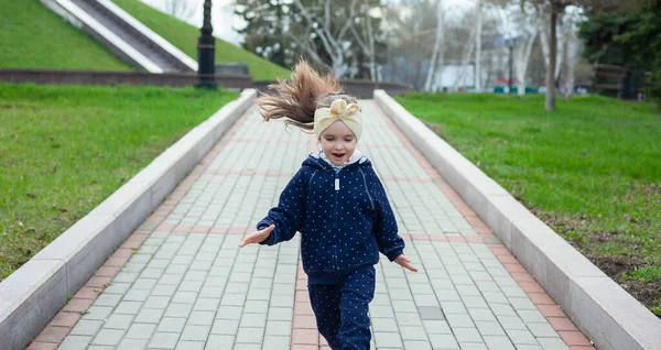 Little girl runs in the park. Active rest in the park. Cheerful child