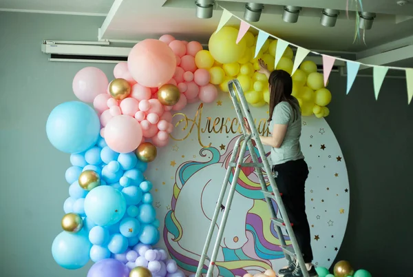 first birthday. decoration with balls. wedding decoration. children's party. birthday party. young woman decorates an evening party. Decoration for a children's party. Birthday decoration.