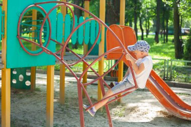 Küçük çocuk parkta oyun oynuyor. Çocuk çocukların kaydırağına tırmanacak..