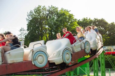 İnsanlar lunaparkta atlıkarıncaya biniyor. Çocuklu aileler atlıkarıncalarda eğleniyor.