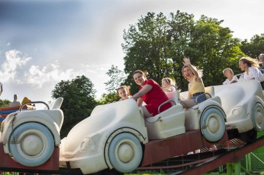 İnsanlar lunaparkta atlıkarıncaya biniyor. Çocuklu aileler atlıkarıncalarda eğleniyor.