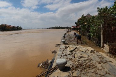 Hoi An, Vietnam, 29 Ekim 2020: Bir adam Thu Bon nehrinin kıyısındaki evinin yanındaki caddeyi temizliyor.
