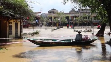 Hoi An 'daki Thu Bon Nehri taşkınlığından hasar gören ünlü bir köprüyü tamir etmek için teknede çalışan bir adam var.