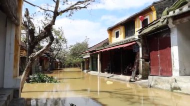Tayfun Mollave 'den sonra Hoi An' da sel basmış bir sokakta, evlerinin verandasında bir aile.