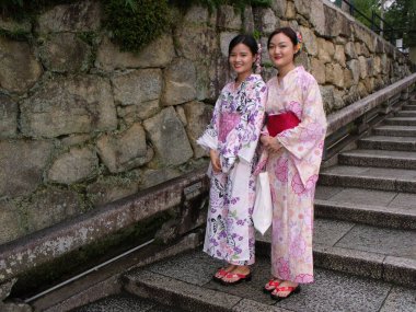 Kyoto, Japonya, 13 Temmuz 2016: Kyoto tapınağının merdivenlerinde geleneksel renkli kimono giyen iki kız