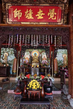 Hoi An, Vietnam, 18 Şubat 2021: Phap Bao Tapınağı 'nın ana salonunda Buda' nın farklı temsilcileriyle sunak. Hoi An, Vietnam. Dikey görünüm