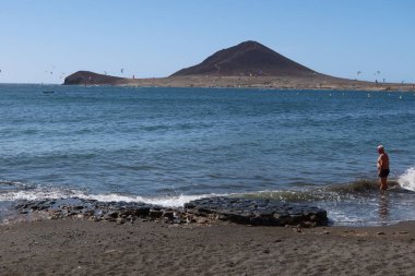 El Medano, Tenerife, İspanya, 2 Kasım 2025: Bir adam El Medano 'daki Playa Chica' da yüzmekten zevk alıyor.