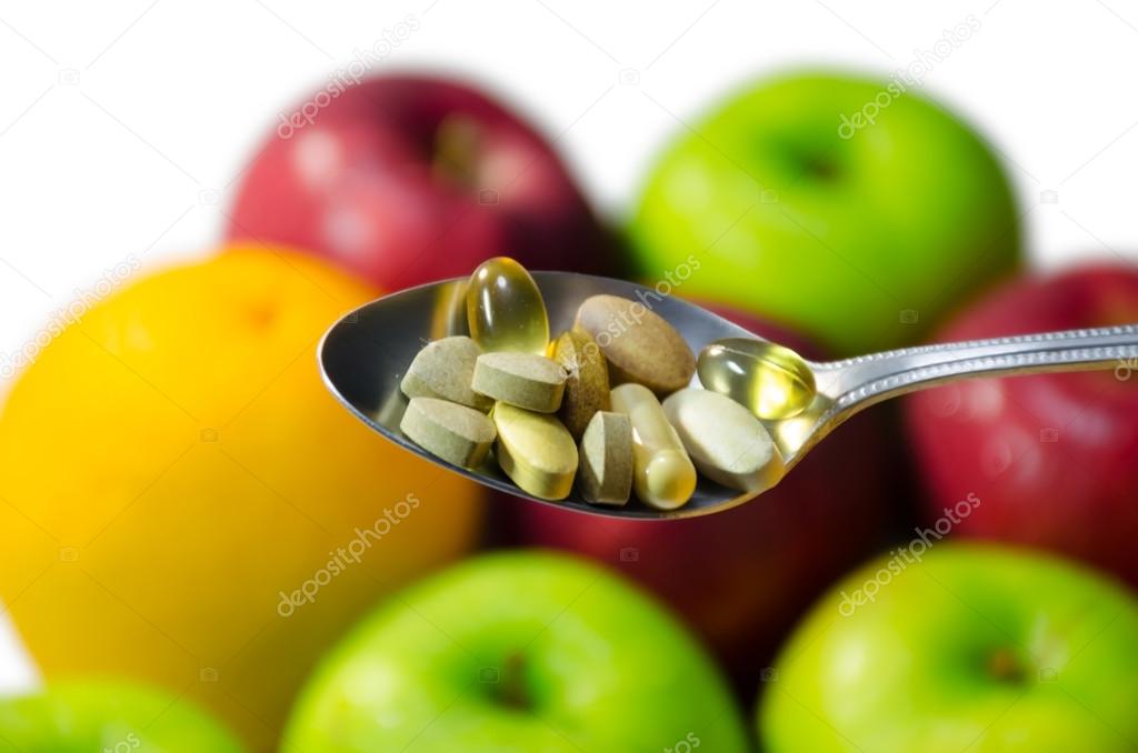 Assorted vitamins and nutritional supplements in serving spoon. 