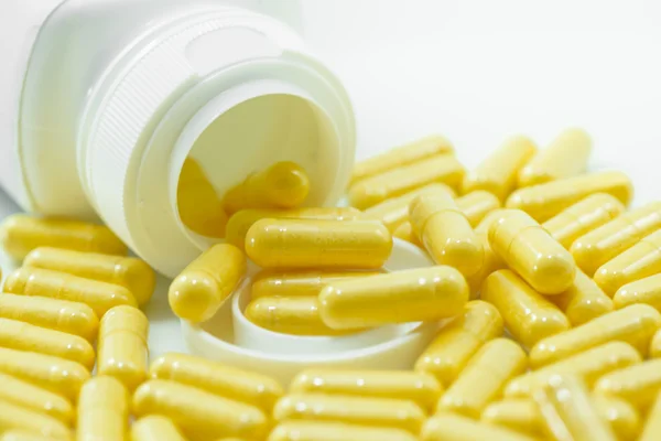 Cápsulas de drogas amarelas derramadas do recipiente — Fotografia de Stock
