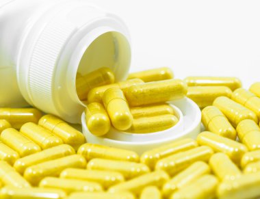 Kapsayıcıdan dökülen sarı ilaç kapsül  